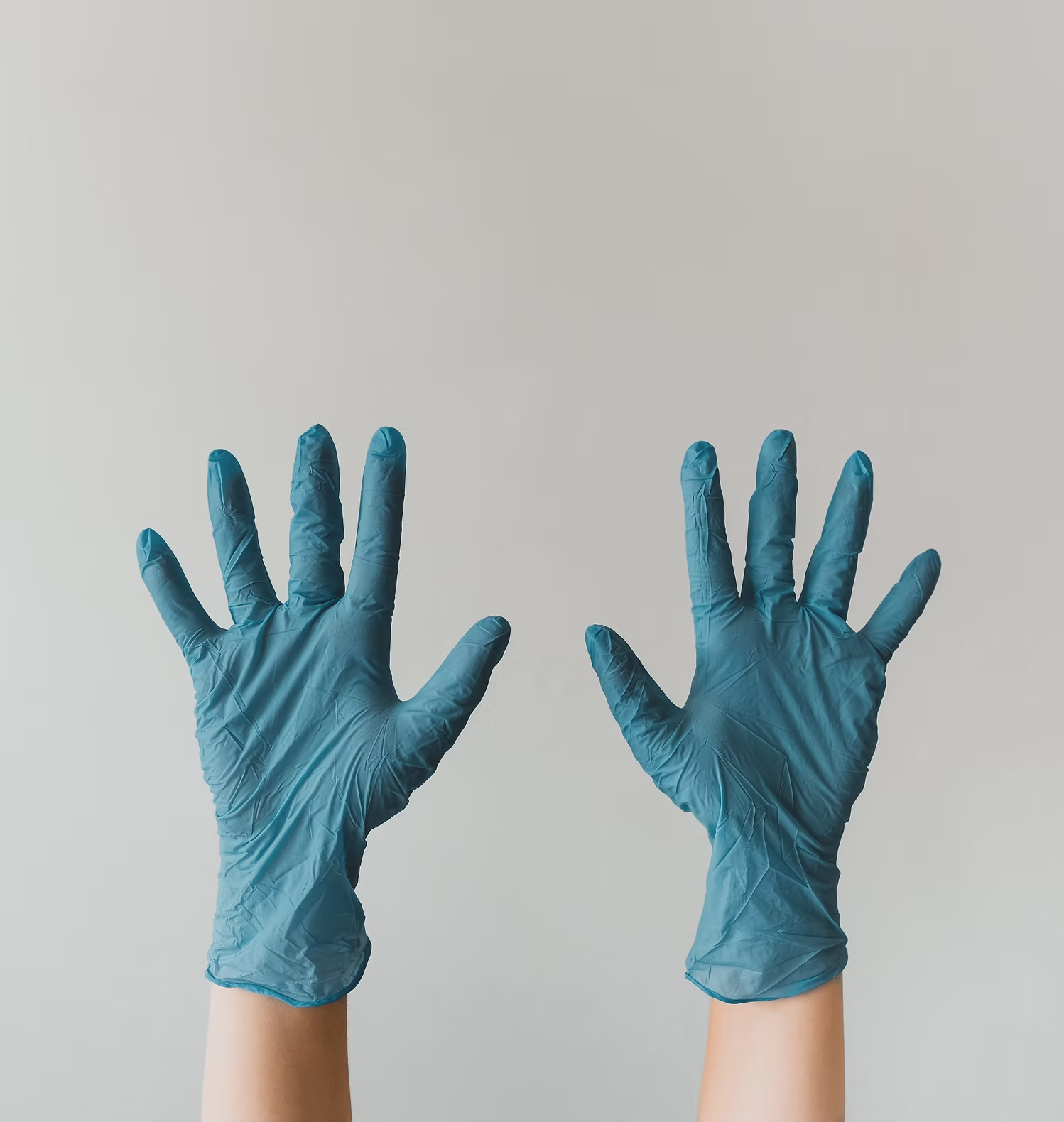 Zwei Hände mit blauen Schutzhandschuhen als Symbol für Arbeitssicherheit